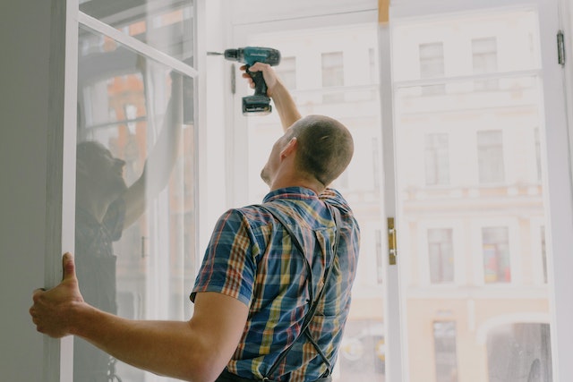 person fixing window with drill